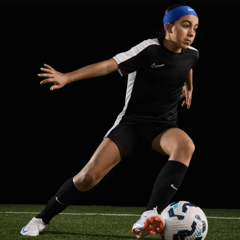 A girl dribbling in white Nike Mercurial Vapor 16 Pro junior boots